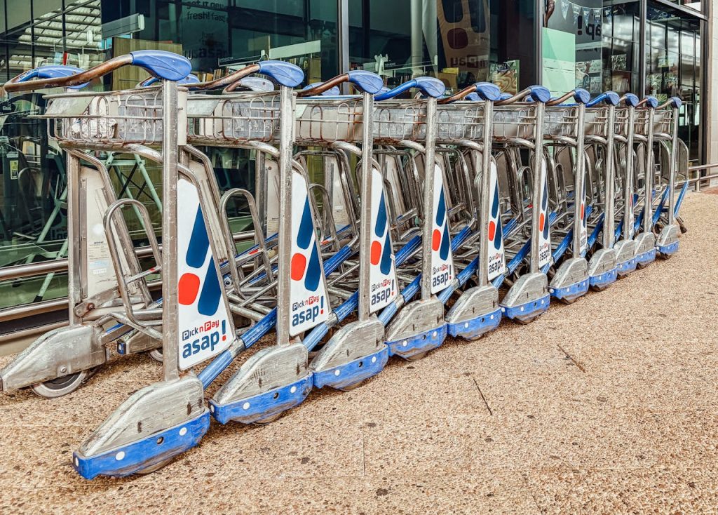 Neatly arranged row of luggage trolleys outside an airport terminal, showcasing travel essentials.